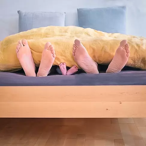 Familia descansando en una cama: el colecho sin condiciones seguras aumenta el riesgo para el bebé.